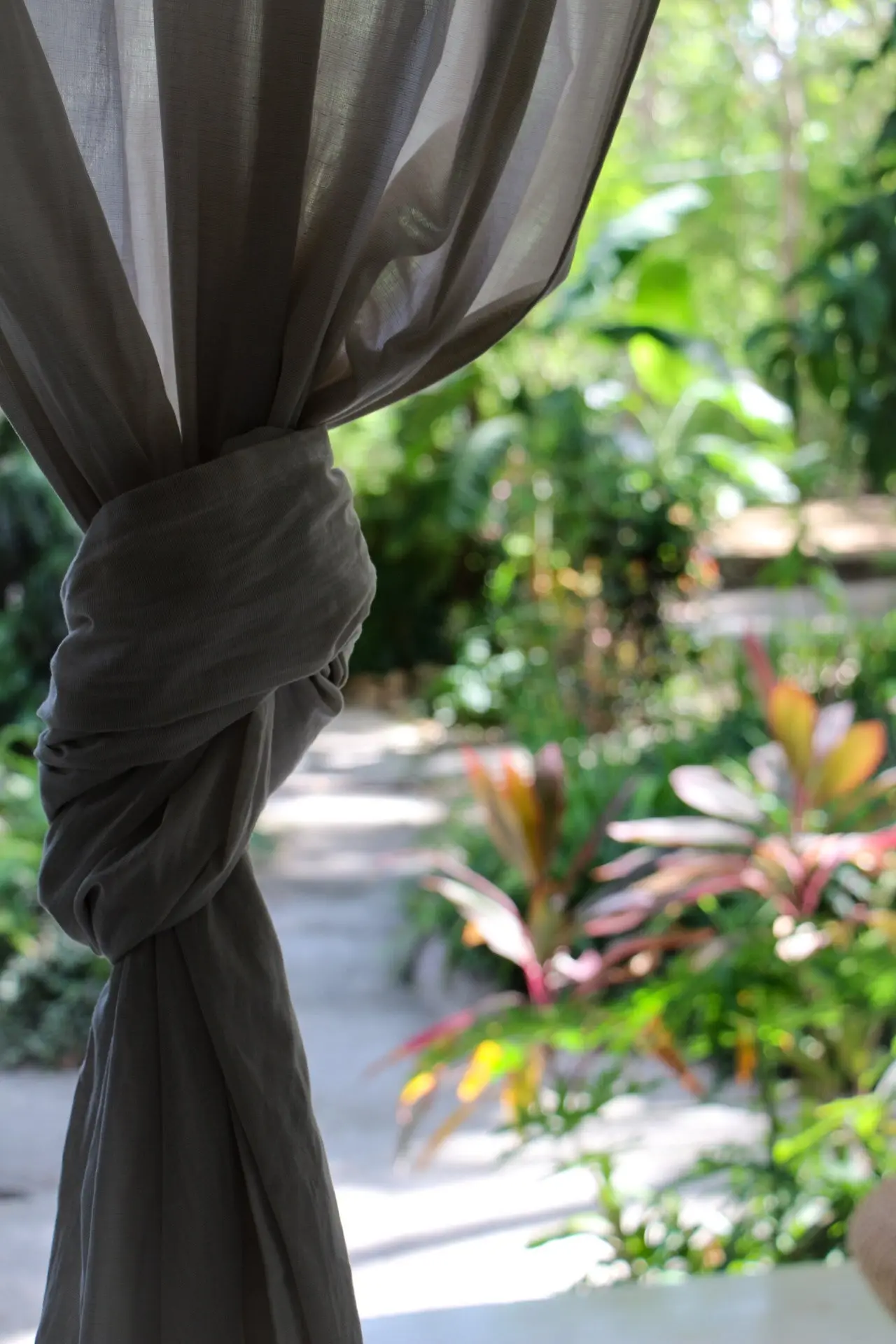 A curtain tied back to a garden view at Naya Nosara